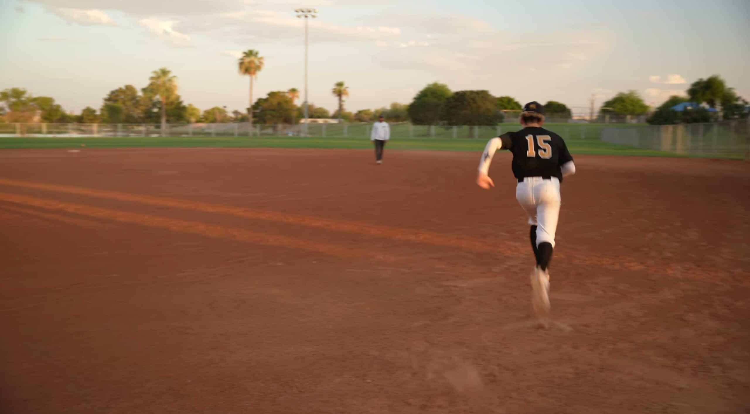 #15 Ryker Rux Tries out for AZ Lions Baseball. He is running to first with MLB player Jason Marting the Coach Watching.